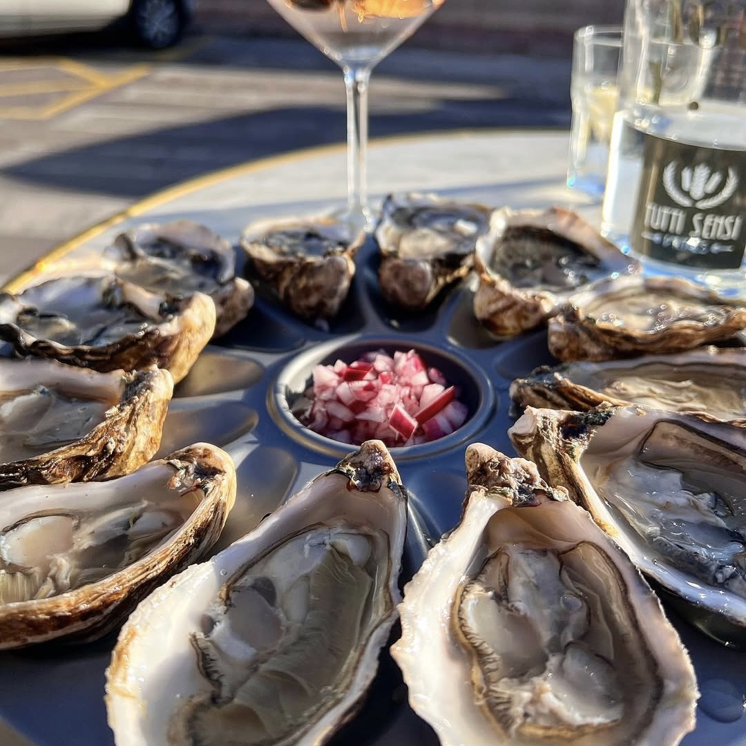 Plato de ostras frescas con copa de vino blanco en Tutti Sensi, restaurante italiano frente al mar en Puerto Portals, Portals Nous, Calvià, Mallorca