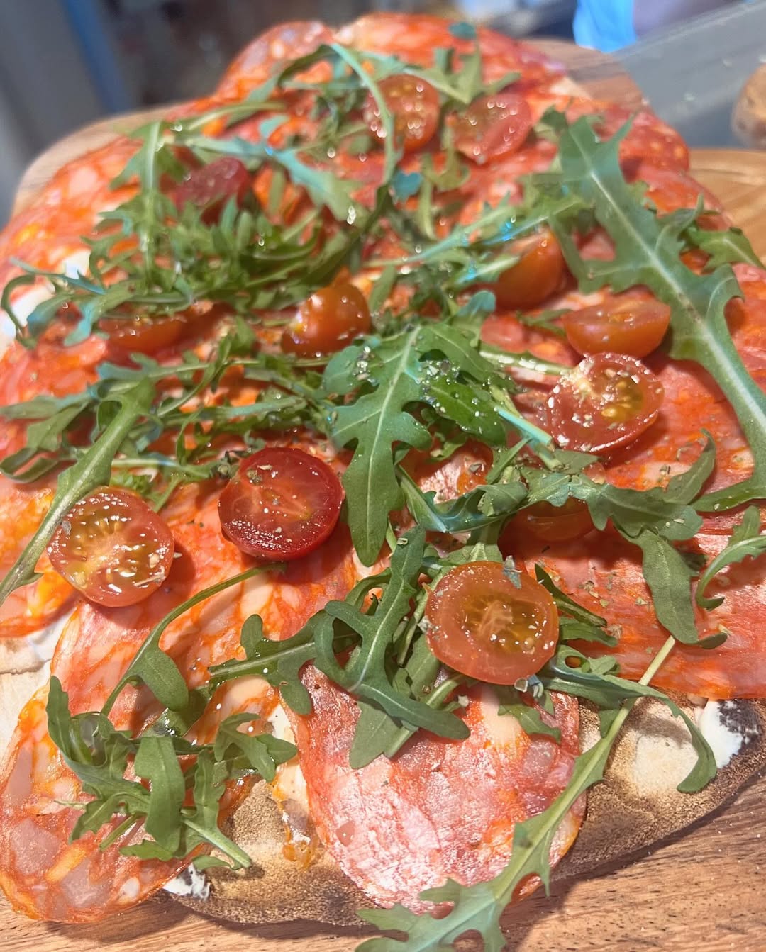 Imagen de cerca de una pizza italiana con masa gruessa, tomate, peperoni, mozzarella derretida y albahaca fresca en Tutti Sensi, el mejor restaurante en Puerto Portals, Calvià, Palma de Mallorca.